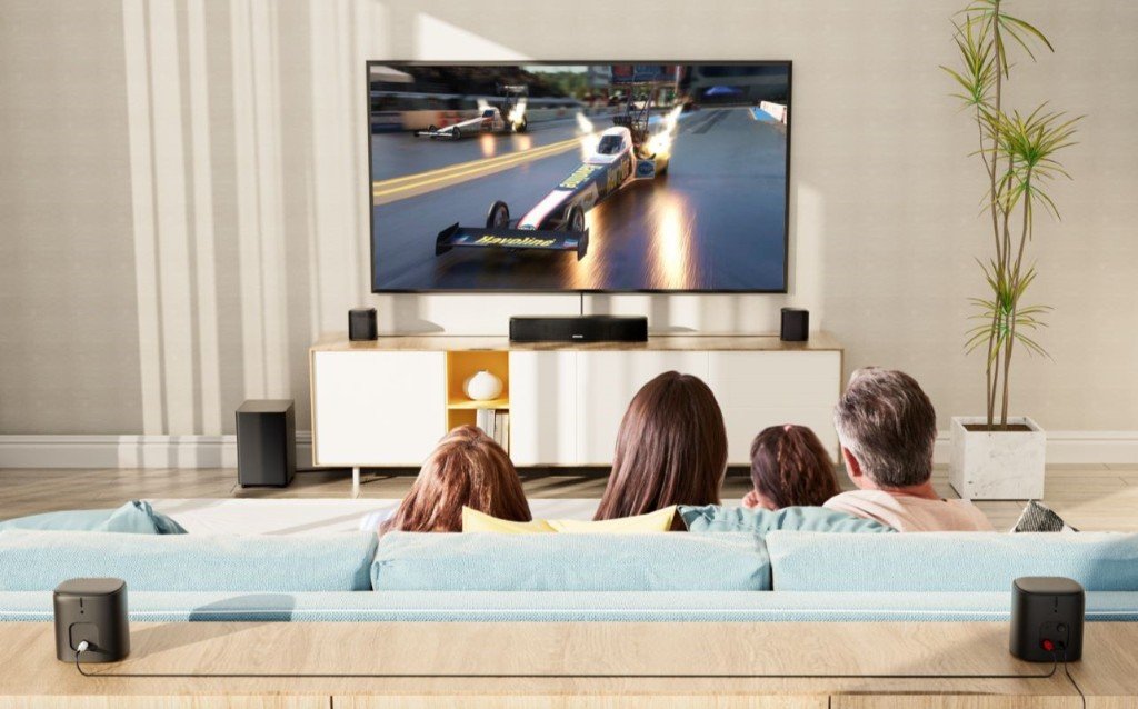 Family watching motorsport on a large TV with surround sound speakers